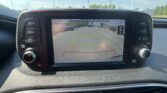Car dashboard screen showing rear‑view camera with parking guidelines and the message “Check surroundings for your safety.”