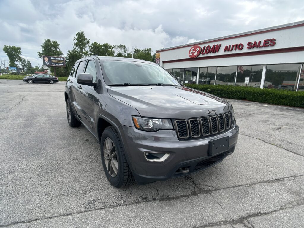Gray Jeep SUV parked diagonally in a dealership lot with EZ Loan Auto Sales building in the background.