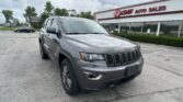 Gray Jeep SUV parked diagonally in a dealership lot with EZ Loan Auto Sales building in the background.