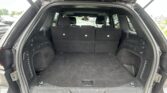 Open SUV trunk showing a spacious cargo area with back seats in place and dark carpeting.