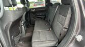 Rear passenger seat area of a black SUV with three-seat bench, headrests, and visible seat belts, viewed from the open rear door