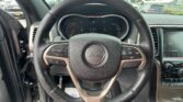 Driver's view of the Jeep steering wheel with the instrument cluster and touchscreen dashboard in the background, from the driver seat.