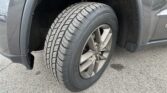 Close-up of a car wheel and tire inside the front fender well, showing the tread pattern and alloy rim.
