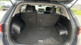 Open SUV trunk with folded rear seats visible in a parking lot, showing spacious cargo area and rear tailgate hinges above it.