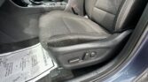 Front interior view of a car showing the center console, gear shifter, and black fabric seats with a seatbelt buckle visible near the seat edge.