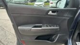 Inside a car door panel with window controls; outside is a busy parking lot full of cars at a dealership momentarily visible through the window.