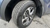 Close-up of a car tire and wheel with a wet, droplet-covered fender nearby.