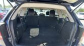 Open rear hatch of a dark blue SUV showing an empty cargo area with folded third-row seats and a parking lot behind.