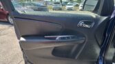 Interior of a car door panel with window controls and chrome handle; outside visible parking lot with cars in background.