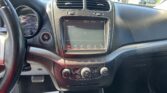 Interior car dashboard focusing on the center touchscreen framed by two air vents; steering wheel on the left edge is visible.