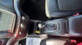 Car interior focusing on center console with gear shifter, climate controls, and leather seats; a paper on the floor reads 'Take pride...'.