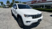 White Jeep SUV parked in front of EZ Loan Auto Sales dealership under a blue sky