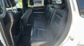 Interior of a black leather SUV; rear seating with two captain’s chairs and a back row, doors open to show outside parking lot.