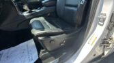 Open car door showing black leather front seat and center console with gear shifter, Jeep sill plate, and hanging seatbelt.