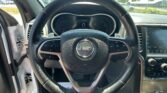 Close-up view of a Jeep steering wheel and dashboard from the driver’s seat, with the instrument cluster visible and the windshield in the background.