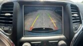 Rearview camera display on car dashboard showing guiding lines (green/yellow/red) with 'Check Entire Surroundings' text.