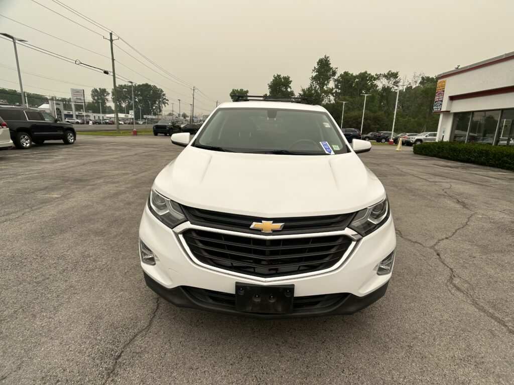 Front view of a white Chevrolet SUV parked in a car dealership lot with other vehicles in the background