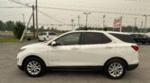 White Chevrolet Equinox parked in a car lot with a dealership sign and power lines in the background