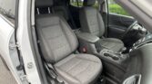 Interior of a car showing two front seats with grey quilted fabric, center console, and cupholders; steering wheel on the right side suggests a right-hand-drive vehicle; passenger door open.