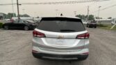 Rear view of a silver Chevrolet Equinox parked in a car lot with other vehicles and power lines overhead.