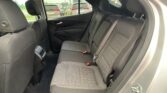 Rear passenger seating in a dark fabric SUV: three-seat row with headrests, visible seat belts, and a view of parked cars through the windows behind the front seats.