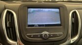 In-car display showing the rearview camera view with orange guiding lines while backing into a parking lot.