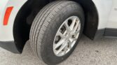 Close-up of a silver car wheel and tire, showing tread and the Chevrolet emblem on the alloy rim near the fender.