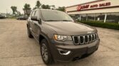 Gray Jeep SUV parked angled in the foreground outside EZ Loan Auto Sales storefront, dealership sign visible in the background