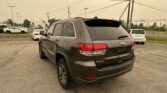 Rear view of a dark gray Jeep SUV in a parking lot, with power lines overhead and other cars in the background.