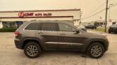 _gray SUV parked at a car dealership lot in front of a building with a red E-Z LOAN AUTO SALES sign_ behind-the-scenes view showing vehicles and a flag in the background