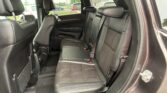 Rear passenger area with three black leather seats, headrests, and visible seat belts in an SUV interior.