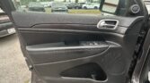 Interior car door panel with chrome door handle, window controls, and speaker on the right side