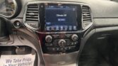 Car dashboard center touchscreen shows Climate Off with climate controls beneath and air vents on each side, view through windshield outside.