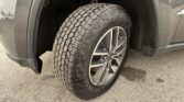 All-terrain tire mounted on a silver SUV wheel inside the wheel well, with visible tread and suspension above the tire.