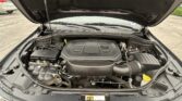 View under the car hood showing the engine bay with battery, fluid reservoirs, and wiring.