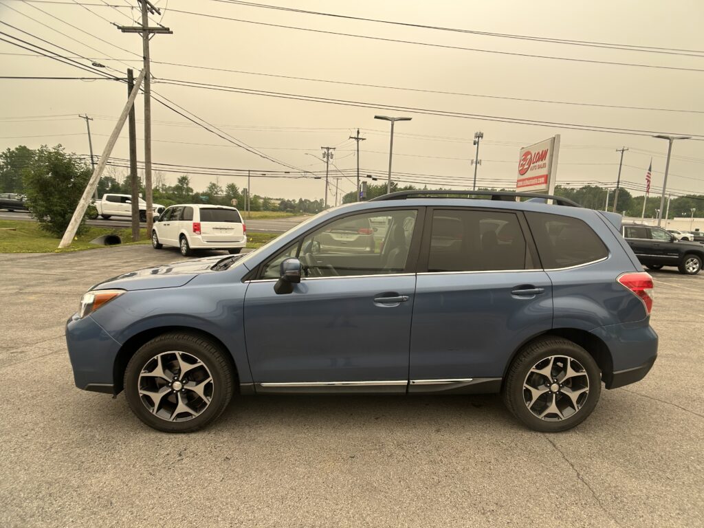 Blue SUV parked in a dealership lot with power poles and a distant EZ LOAN Auto Sales sign in view.
