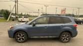 Blue SUV parked in a dealership lot with power poles and a distant EZ LOAN Auto Sales sign in view.