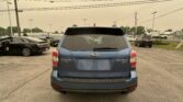 Rear view of a blue Subaru Forester XT parked in a lot with other cars and overhead power lines nearby.