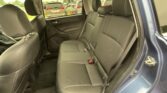 Rear passenger seating in a black-leather SUV, seen from the open side door with headrests and seat belts visible.