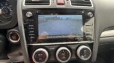Car interior dashboard with a touchscreen displaying a rearview camera grid and parking guide lines while the climate controls sit below it.