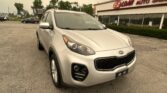 Silver Kia SUV parked in a lot in front of an EZ Loan Auto Sales building with large windows and red sign.