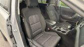 Interior of a car showing front driver and passenger seats with black fabric upholstery and white stitching, center console nearby