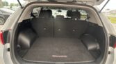 Open hatchback showing spacious trunk with folded rear seats and a black cargo mat labeled 'SPORTAGE' in a SUV parked at a lot