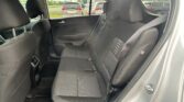 Back seat view inside a dark fabric car with headrests and visible seat belts, outside parked vehicles in a lot.