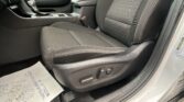 Front interior of a dark cloth car seat area with center console, gear shifter, and a paper floor mat visible on the floor.