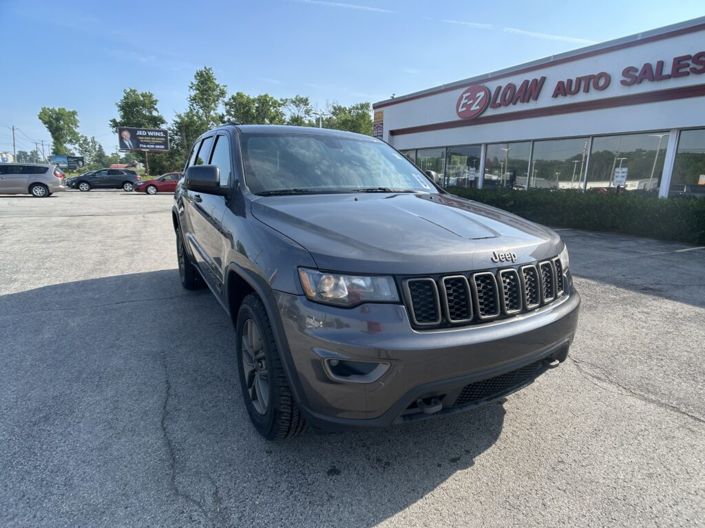 Grey Jeep SUV parked in front of an EZ Loan Auto Sales building on a sunny day.
