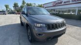 Grey Jeep SUV parked in front of an EZ Loan Auto Sales building on a sunny day.