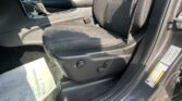 Interior of a car front cabin with a black fabric seat, center console, and seatbelt buckle visible by the passenger seat edge. Sunlight casts shadows on the seat and floor mats.