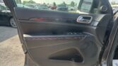 Interior of a car door panel with window/lock controls and chrome handle, parked in a lot outside the window