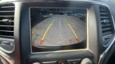 Infotainment screen showing rear-view camera with parking guides (green, yellow, red lines) and 'Check Entire Surroundings' message.